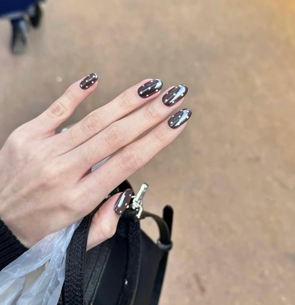 Glossy charcoal almond nails with delicate white polka dots